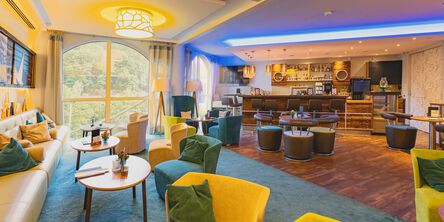 Moderne Bar-Lounge mit bunten Sesseln und einem gut beleuchteten Tresen